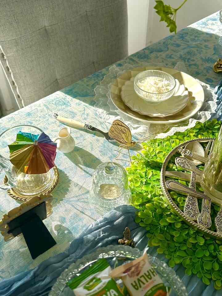 Blue tablecloth and gold accents adorn a dining table set up with a home cafe style ambiance.