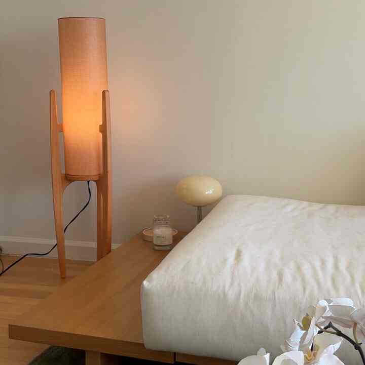 Beige and wood tone bedroom space featuring warm lighting and a table lamp on the side table creating a cozy atmosphere