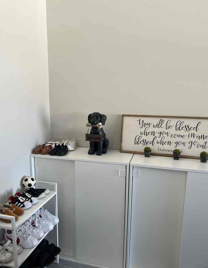 White and wood-tone entrance featuring shoe cabinets with a black dog statue holding a welcome sign, creating a cozy atmosphere