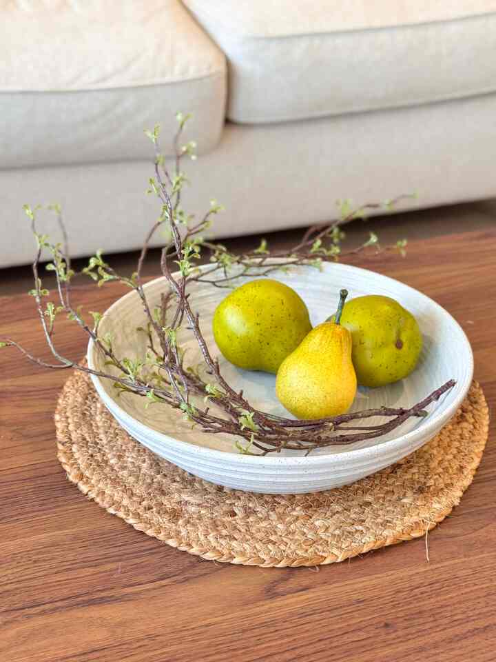 Natural tone living room featuring a wood dining table with a placemat and spiral branches creating a cozy space