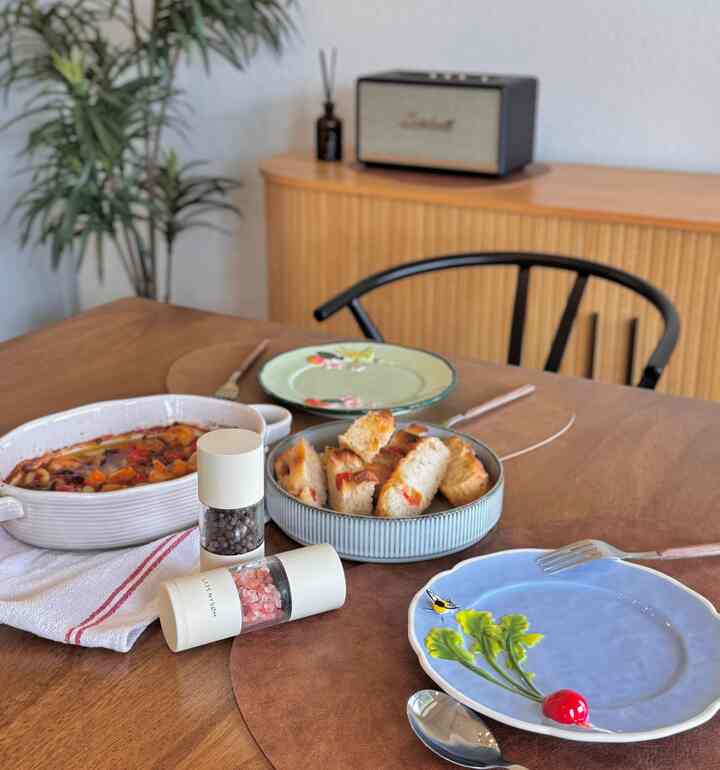 Warm brown dining table featuring assorted plates, kitchen towel, and salt and pepper grinders in a cozy dining setting