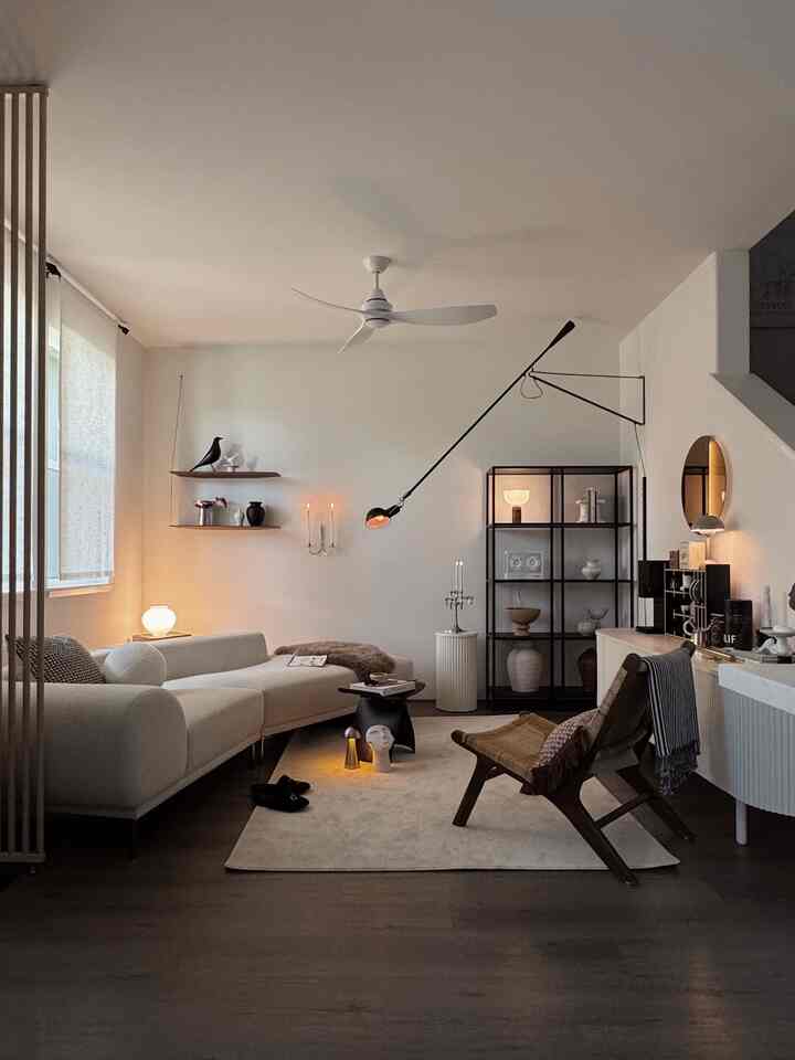 Minimal Japandi living room in white and brown tones featuring sofa, armchair, and layered lighting creating cozy atmosphere