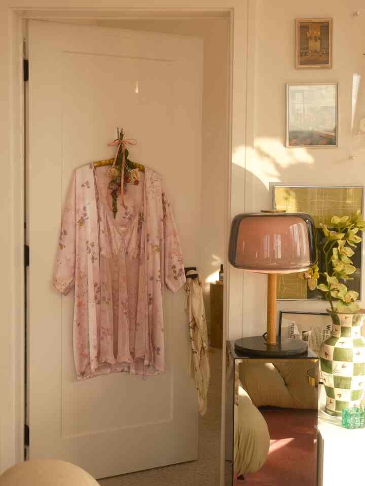 Natural-toned space featuring a warm pink table lamp and a floral robe hanging on an entrance door