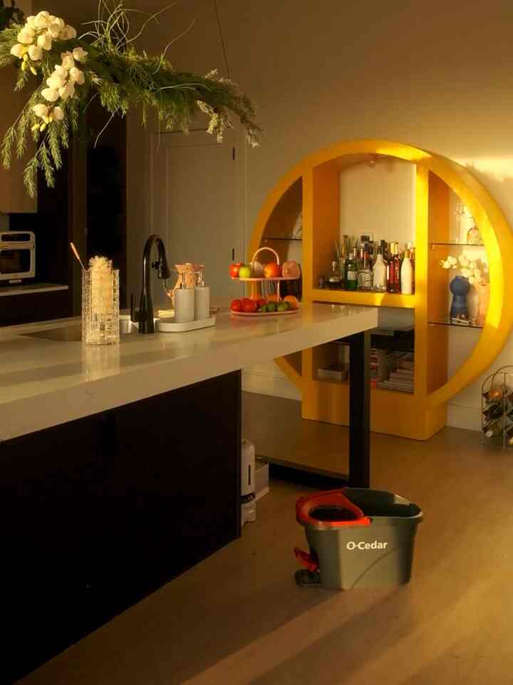 Gold-toned kitchen space featuring a circular gold shelf and a modern kitchen island with warm golden hour lighting