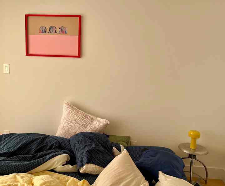 Natural-tone bedroom featuring navy bedding, yellow table lamp, and red picture frame with a cozy atmosphere