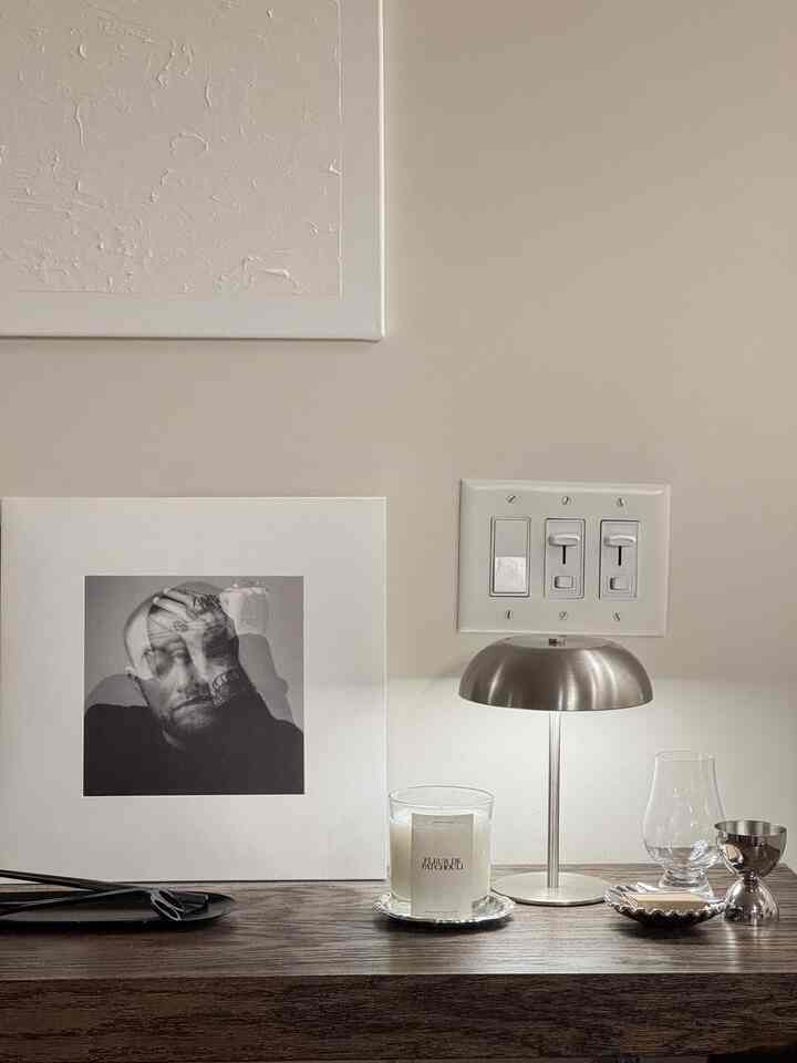 Modern interior space featuring a brown wood tone surface with silver table lamp, home bar glassware, and candle arranged neatly