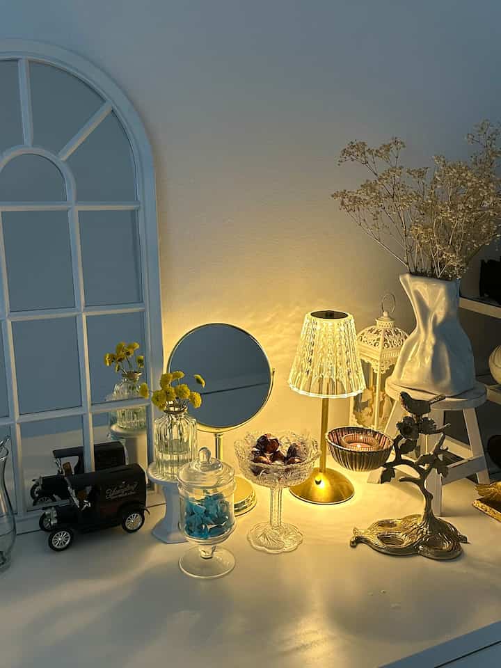 A white entrance table featuring French Country style decor with warm gold lighting and a crystal table lamp creating a cozy atmosphere