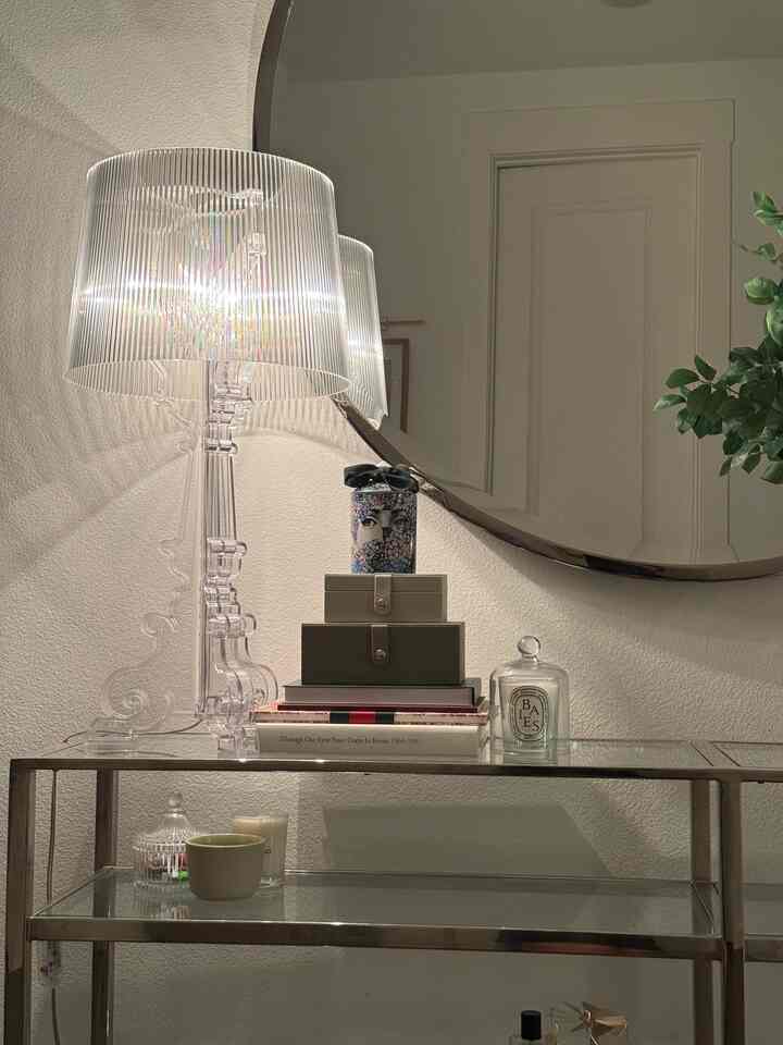 Natural color entrance console table space featuring a transparent table lamp and a round mirror with cozy decor