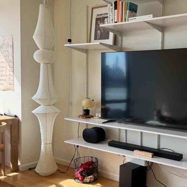 Natural tones and white living room featuring large pendant lamp, TV stand, and bookshelf with cozy atmosphere