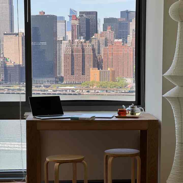 Beige and white-toned kitchen space featuring wooden dining table and stools with remote work and home cafe setup