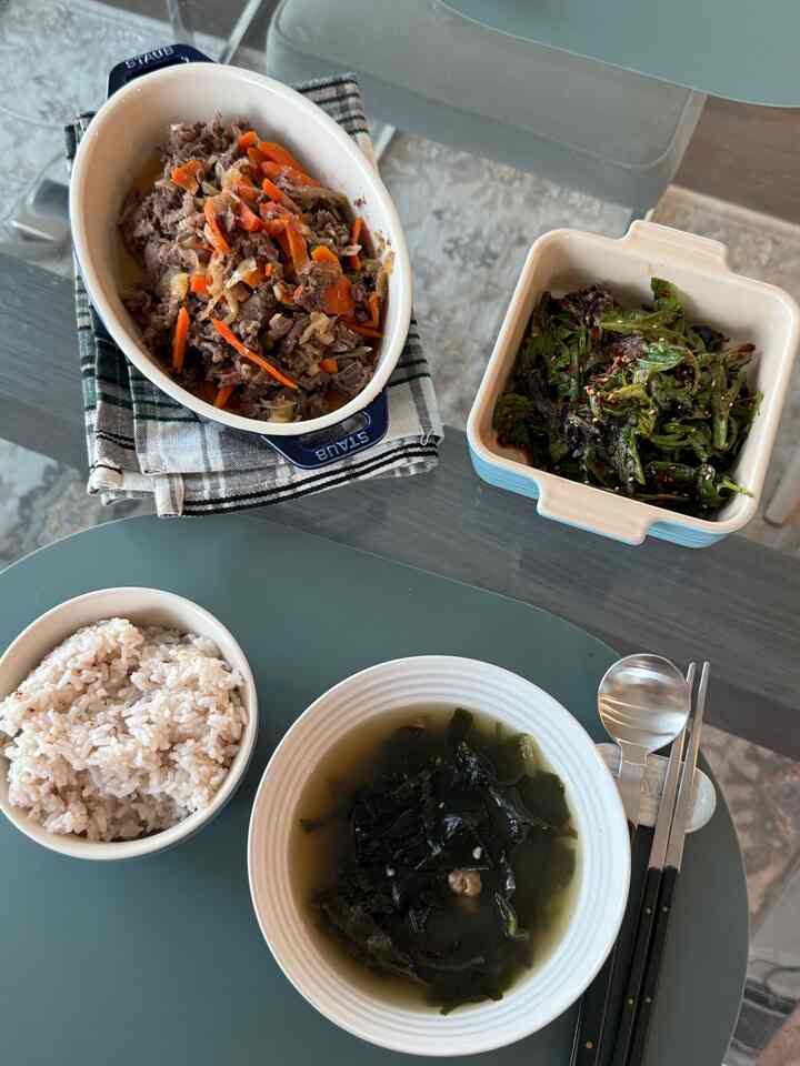 Natural color toned dining space featuring ceramic bowls and stainless steel cutlery for Korean dinner setup