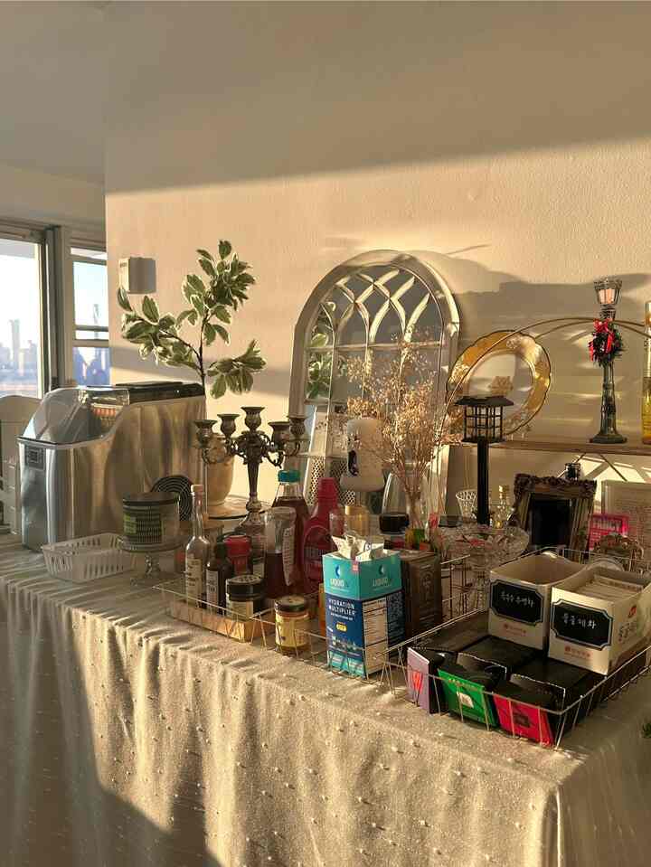 Warm gold and white toned home cafe space featuring arched mirror and maximalist coffee table setup with various decorative elements creating a romantic atmosphere