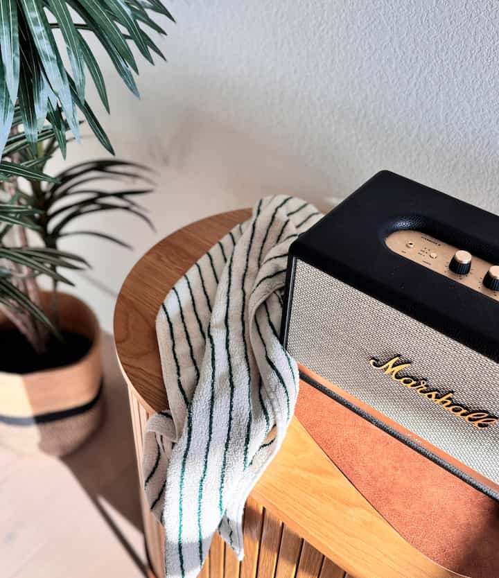 Natural color interior with warm brown wooden furniture, Marshall Bluetooth speaker, and striped towel arranged neatly