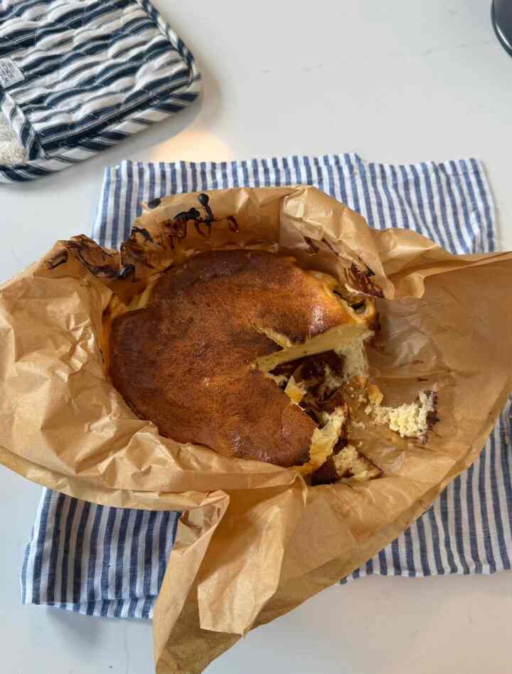 Beige parchment paper with homemade cheesecake and blue striped kitchen towel in a cozy kitchen setting