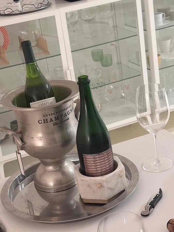 Silver and white toned dining room featuring wine bottles, wine glasses, and silver tray in a clean home bar setting