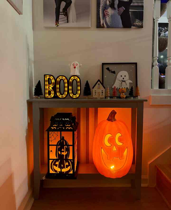 Orange and black themed entry hallway featuring Halloween console table decorations with glowing lights creating cozy ambiance