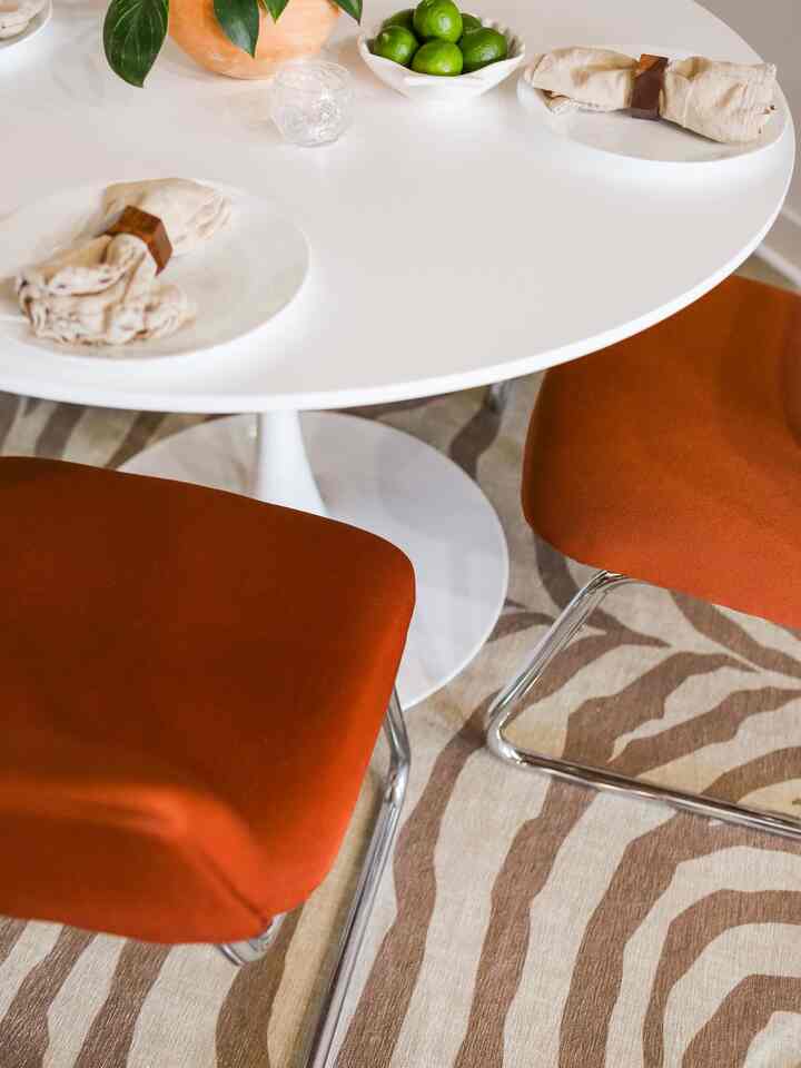 Up close and personal with the dining details! 🍊 The texture of that rust upholstery next to the crisp white table is so good. And that zebra rug is the foundation for all the fun! Little pops of green (limes!) to finish the look. 🌿✨
#DiningDetails #TableSetting #RustAesthetic #ZebraRug #Ruggable #MidCenturyModern #ColorPalette #InteriorStyle #Dinnerware 

