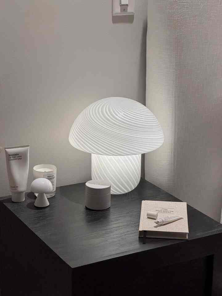 White and black toned bedroom nightstand featuring minimalist Scandinavian table lamp and candle, creating a cozy atmosphere