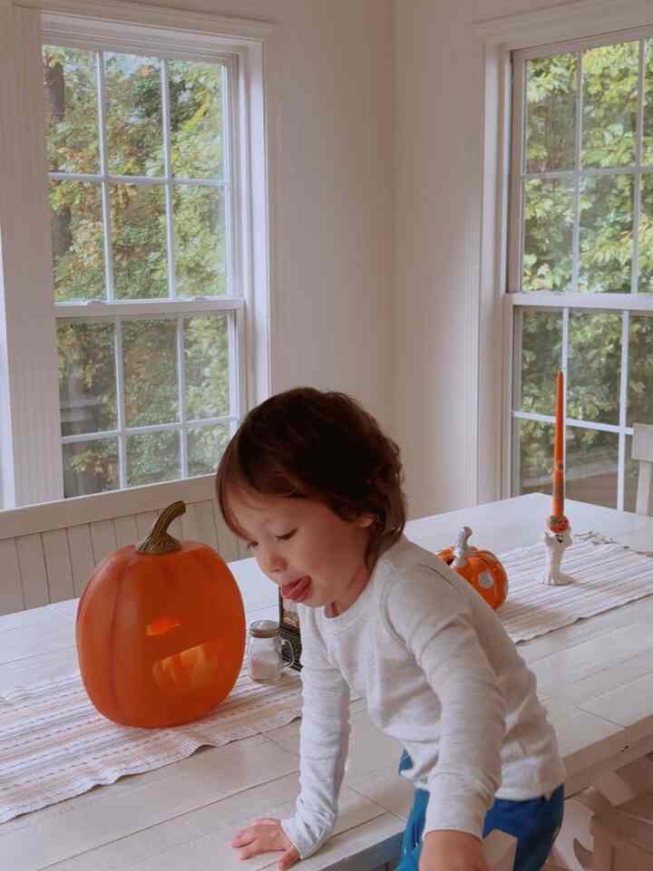 White and orange toned dining room featuring a child and Halloween decorations, creating a cozy family atmosphere