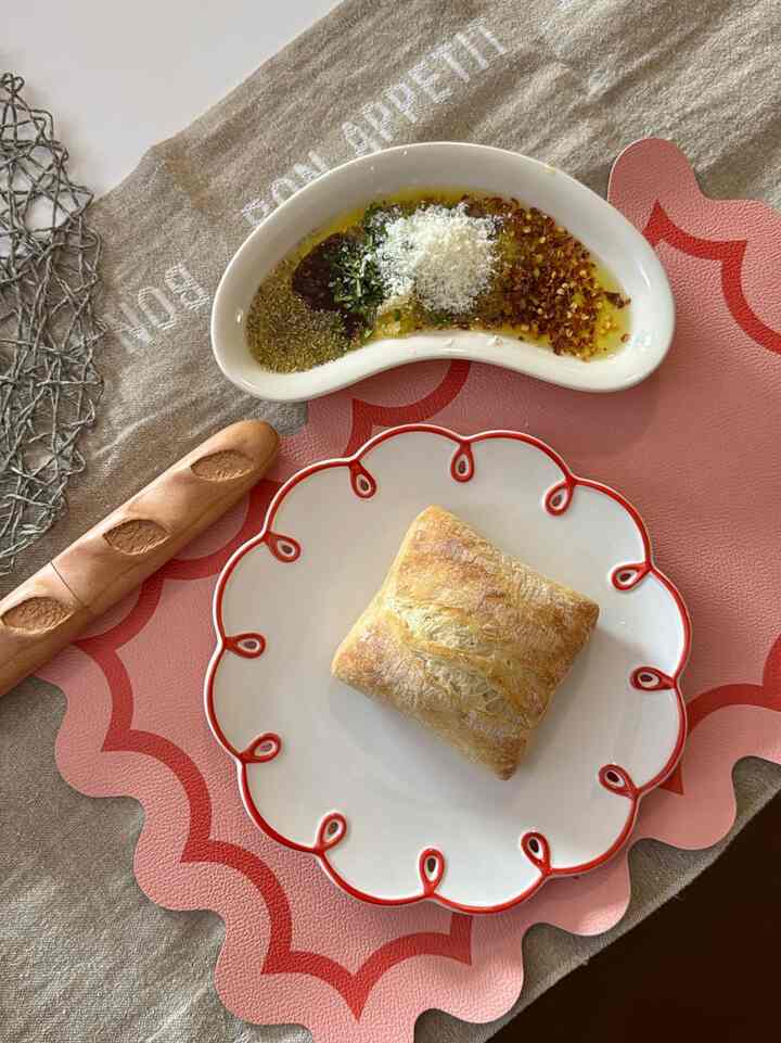 Natural and red toned dining table featuring bread on a decorative plate, creating cozy home cafe vibe