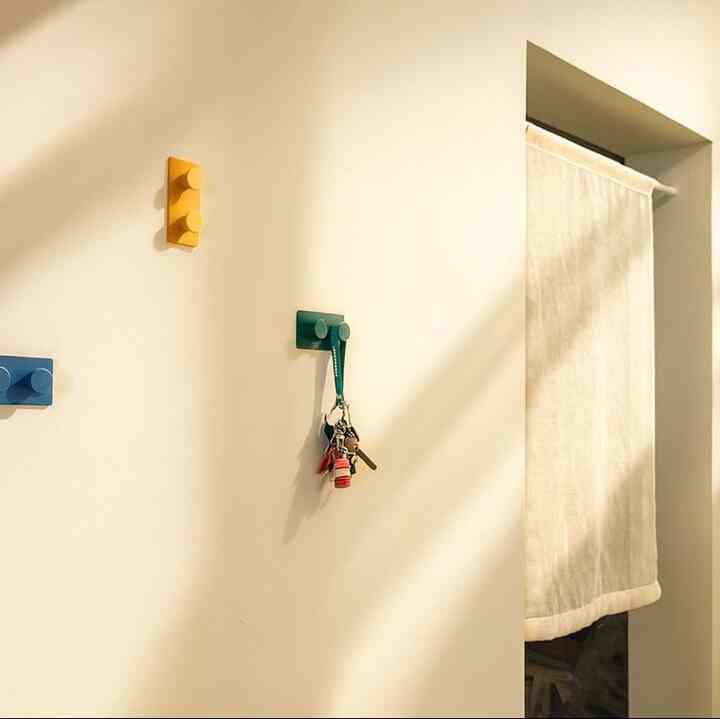 Warm-toned entrance featuring neatly arranged yellow and green wall hooks, creating a cozy atmosphere