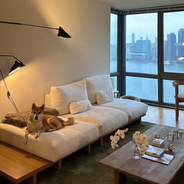 A cozy Japandi living room with natural wood tones and white sofa, featuring rainy views through large windows