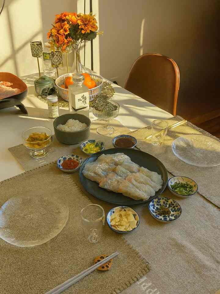 A natural beige-toned dining room featuring a table set with soju, sashimi, and assorted dishes, creating a warm atmosphere
