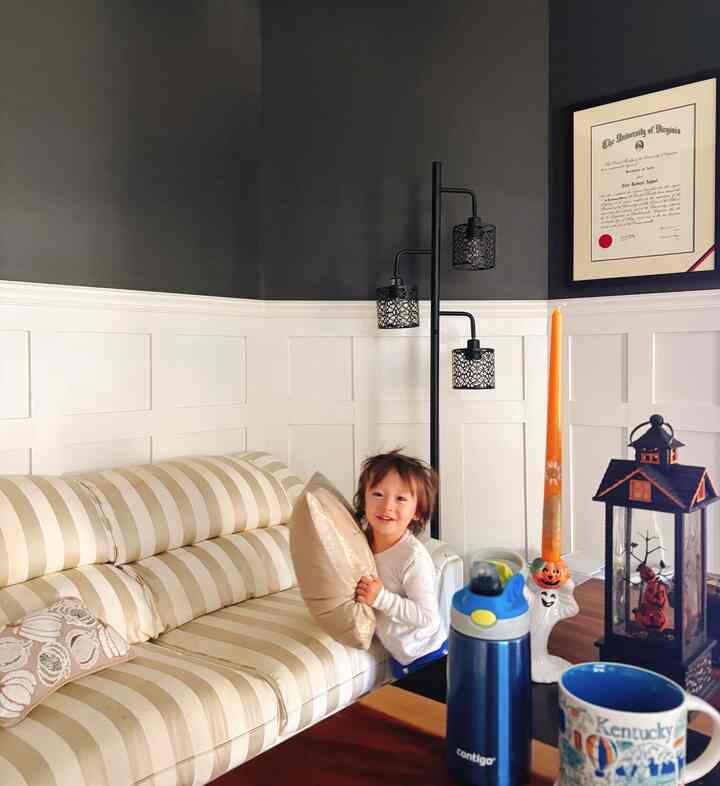 Navy and cream-toned home office space featuring striped sofa and a child in a cozy family environment