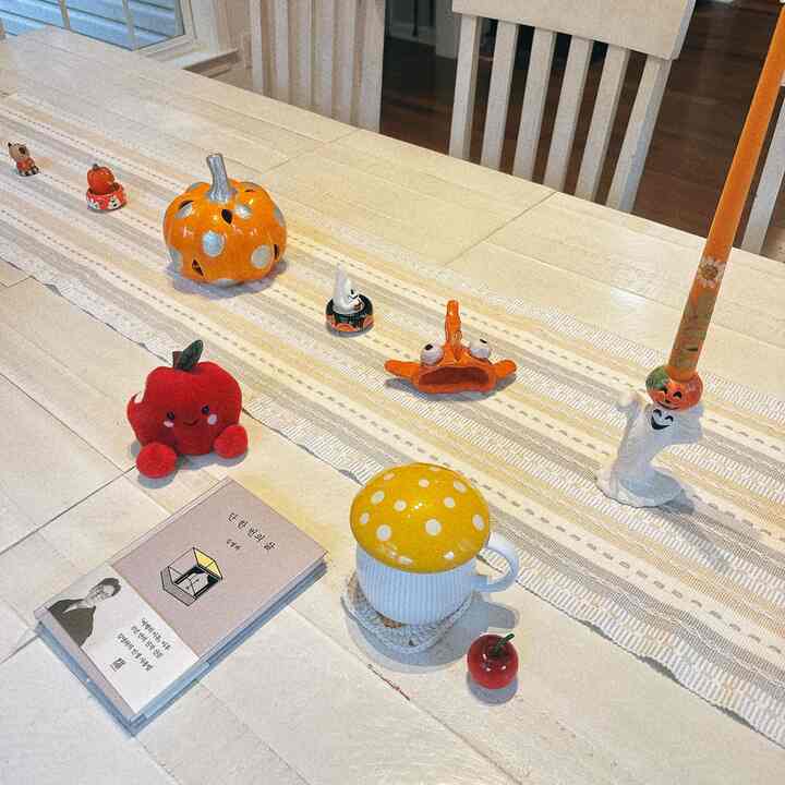 Bright wood tone and white dining room featuring a dining table decorated with Halloween decor and a cute mushroom mug, creating a cozy atmosphere