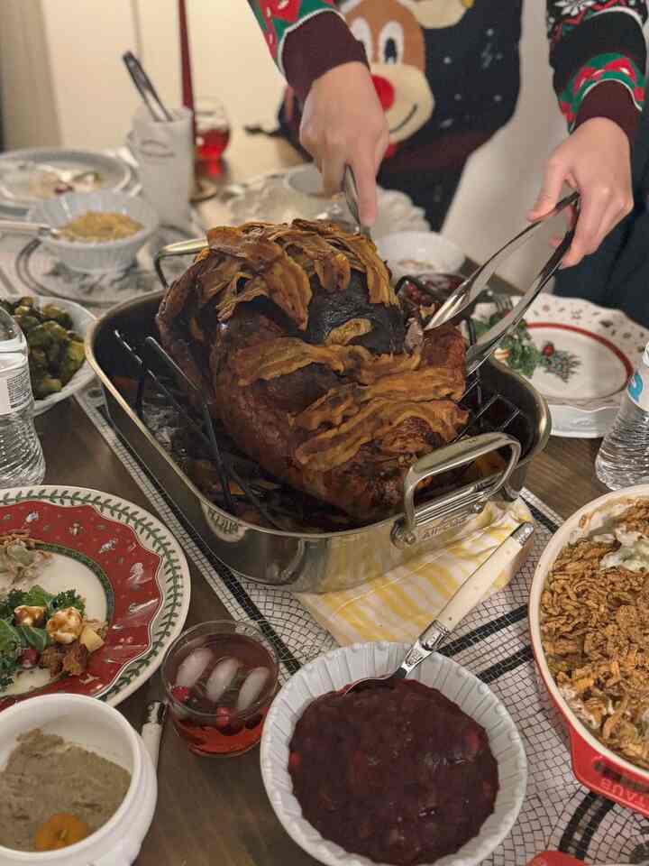 Warm brown roasted turkey and assorted side dishes on a red and white dining table, featuring a cozy home party atmosphere