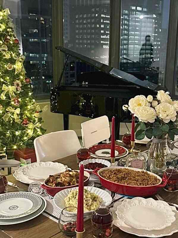 Cozy living room dining table decorated with Christmas tree, dishes, and candles creating festive home party atmosphere