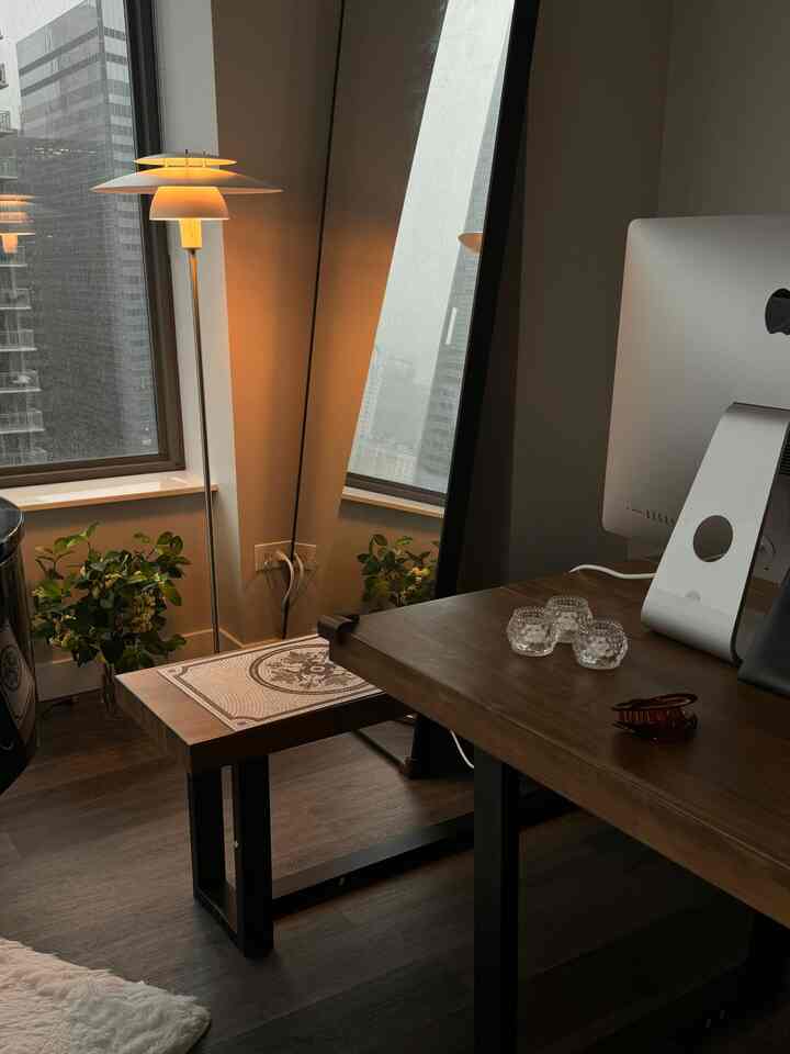 Warm natural-toned modern home office featuring a large mirror and floor lamp creating a cozy workspace