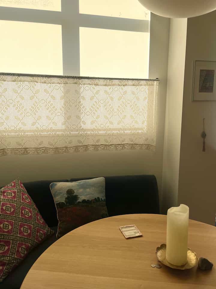 Warm golden hour lighting in a dining room featuring a round wooden table and dark loveseat, creating a cozy atmosphere