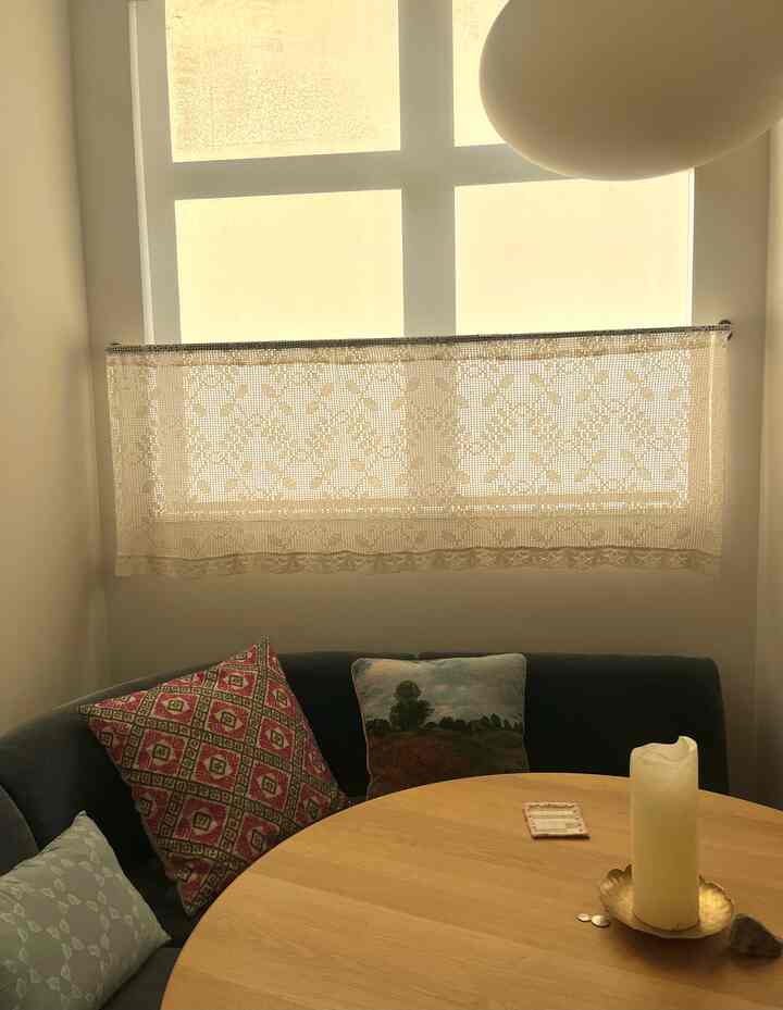 Beige and wood tone dining nook featuring a round table and cafe-style lace curtain creating a cozy atmosphere