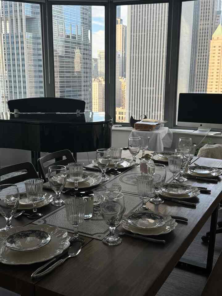 Modern dining room in white and black tones, featuring a carefully set dining table and a grand piano in a sophisticated space