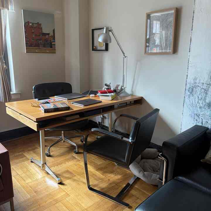 White and wood tone home office with mid-century modern desk and chairs arranged in a cozy setting