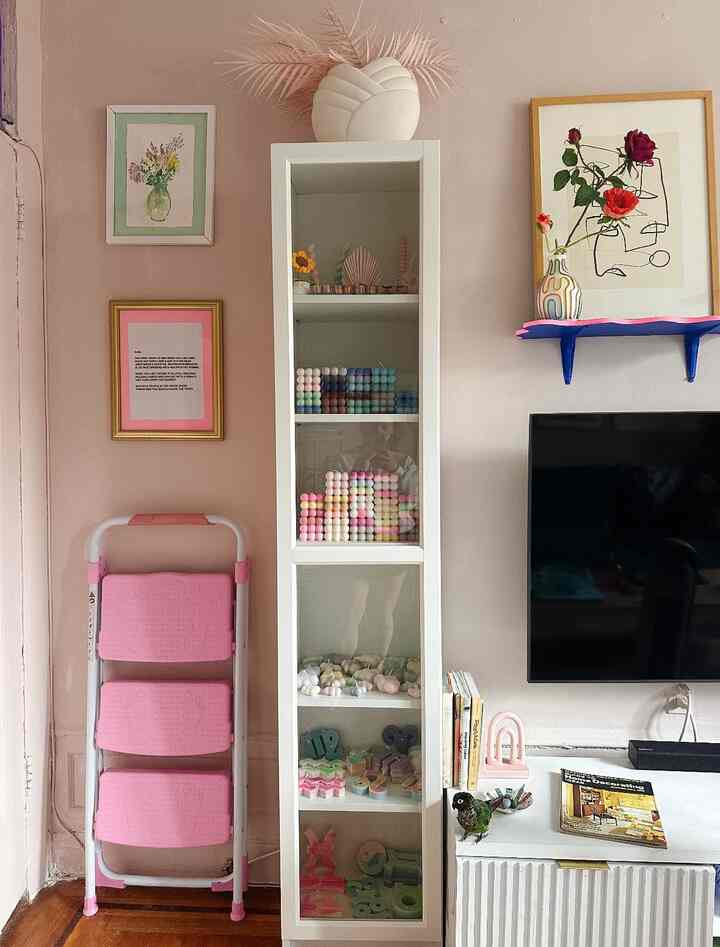 Modern space with pink-toned walls and storage cabinet, featuring colorful candles and art decor