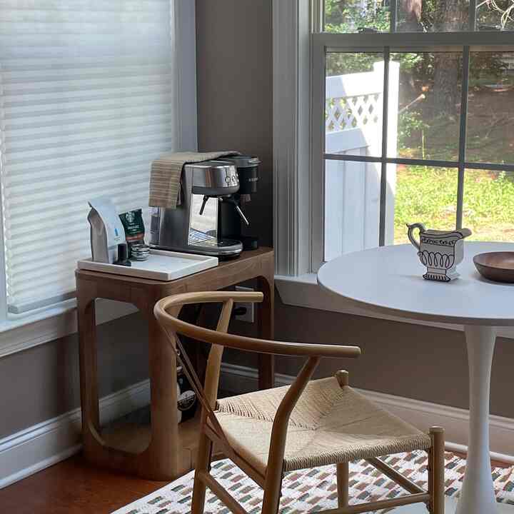 White and natural toned dining room featuring side table with home cafe setup, creating a cozy atmosphere