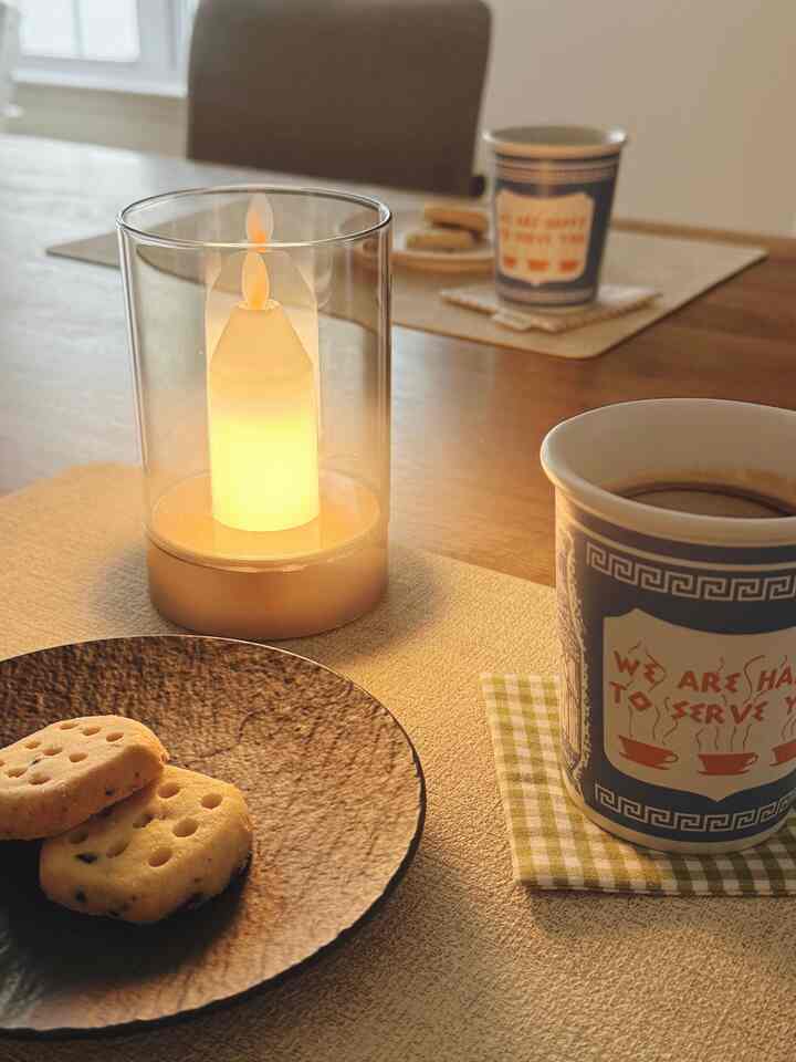 Warm brown and beige toned home cafe setup featuring LED candle light, coffee cups, and cookies on a well-arranged table