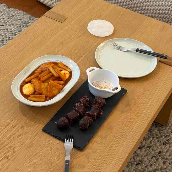 Minimal style dining table in natural wood tone coffee table featuring Korean street food dishes for a cozy lunch setting