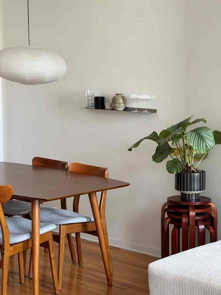 Wood tone natural dining room corner featuring a wooden dining table, chairs, and a round paper lantern lamp overhead creating a cozy atmosphere