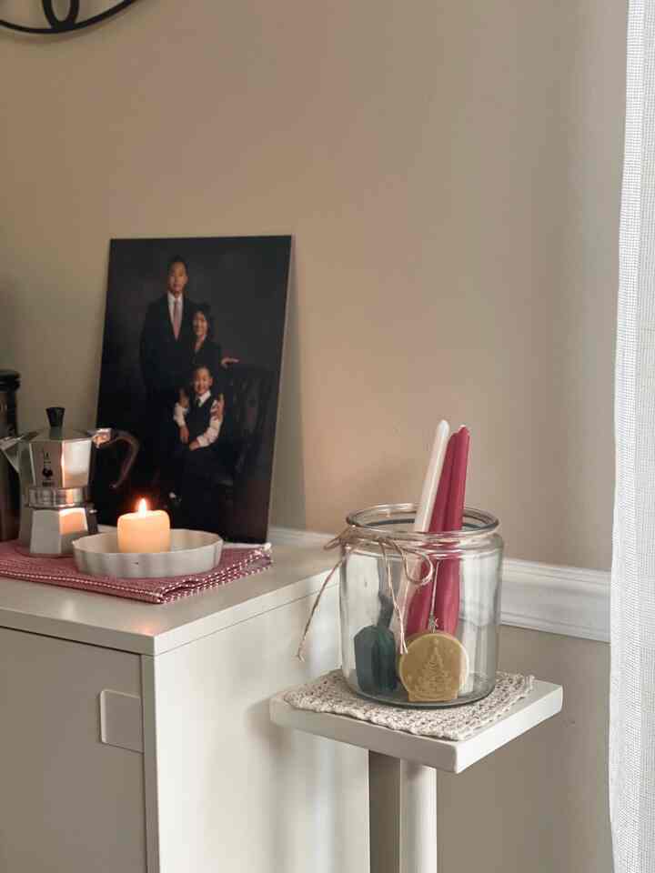 Beige and white toned living room featuring white shoe cabinet, candles, and coffee maker creating a cozy home cafe atmosphere