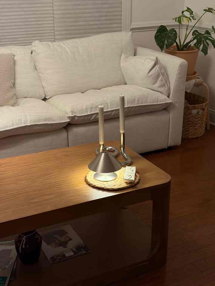 Minimal living room with natural brown wood tones and white sofa, featuring a wooden coffee table with table lamp and candles in center