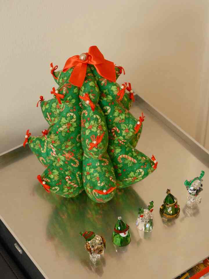 Christmas decor featuring a green and gold fabric Christmas tree and crystal objets on a metallic table