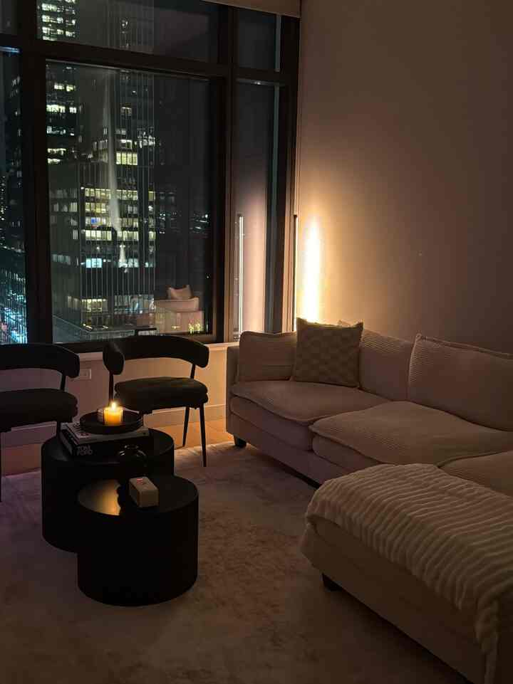 Warm, cozy living room with soft lighting, layered textures, and a city-view backdrop. Neutral tones with black accent furniture for contrast.

#ApartmentInspo #LivingRoomIdeas #CozyAesthetic #ModernLiving #MinimalDecor #NeutralHome #InteriorDesign #CityApartment #SmallSpaceDesign #WarmLighting #HomeStyling #DecorInspiration #ModernApartment #CozyHome
