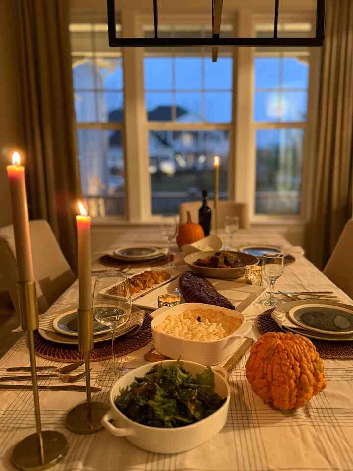 Warm beige-toned dining room with candles and pumpkins on a cozy Thanksgiving table setting