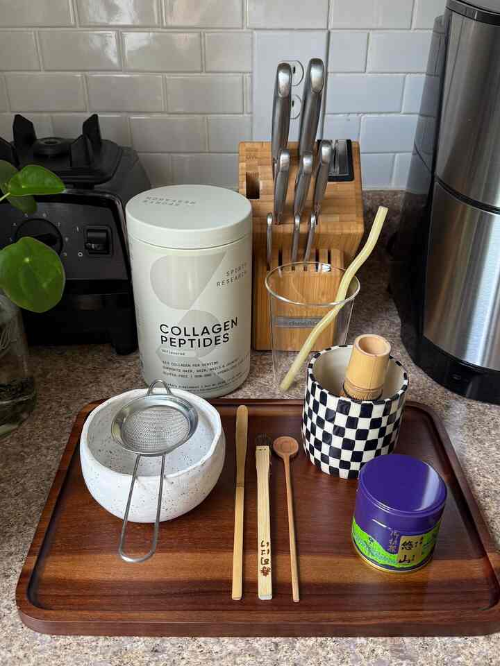 A clean kitchen setup featuring natural wood tones and transparent glassware with traditional matcha tea tools on a wooden tray