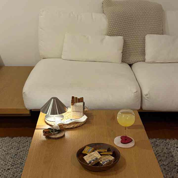 A natural wood tone and white living room featuring a simple Japandi-style coffee table and sofa with a cozy atmosphere