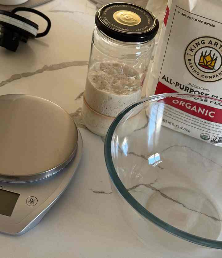 Kitchen space with transparent glass bowl and digital kitchen scale on white marble countertop