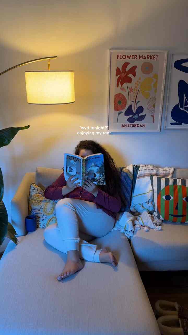 Simple modern living room with beige sectional sofa and arched floor lamp, colorful wall art adds eclectic touch